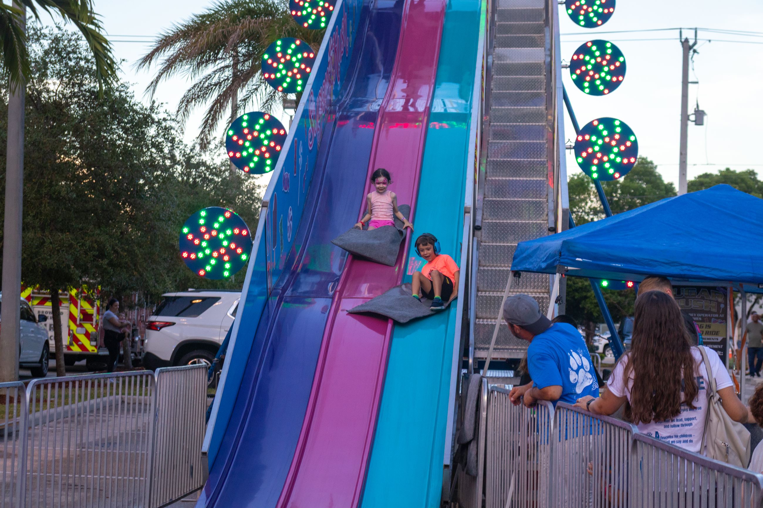 Two children going down slides at sunset
