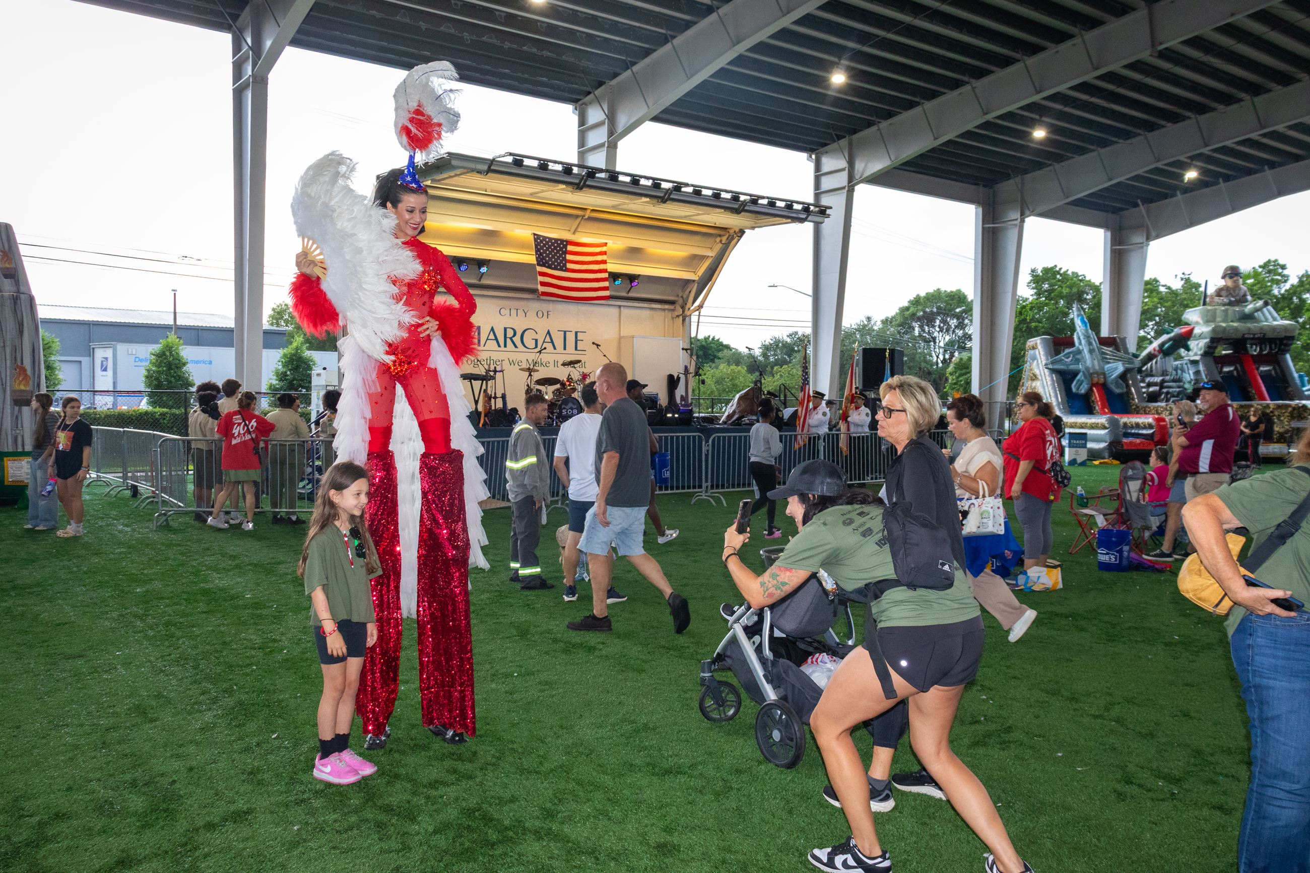 A stilt walker poses with a young attendees under the covered Margate Sports Complex